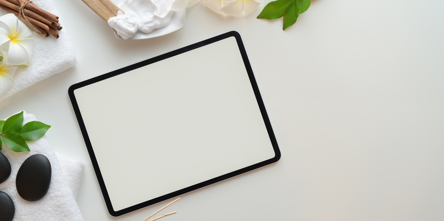 Tablet and skin care products on white table